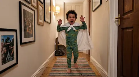 Photo 2: the boy stomping down the hallway, roaring, hands up like claws