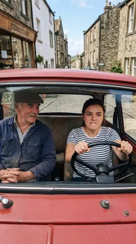 Photo 2: the daughter gripping the wheel while Dad smiles in the passenger seat