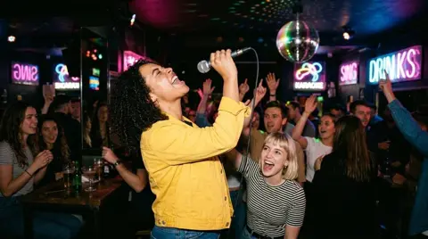 Photo 2: one friend reaching for a high note while the bar sings along
