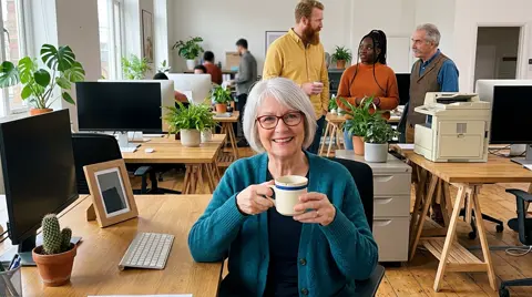 Photo 1: a silver-haired woman at her desk holding a chipped mug
